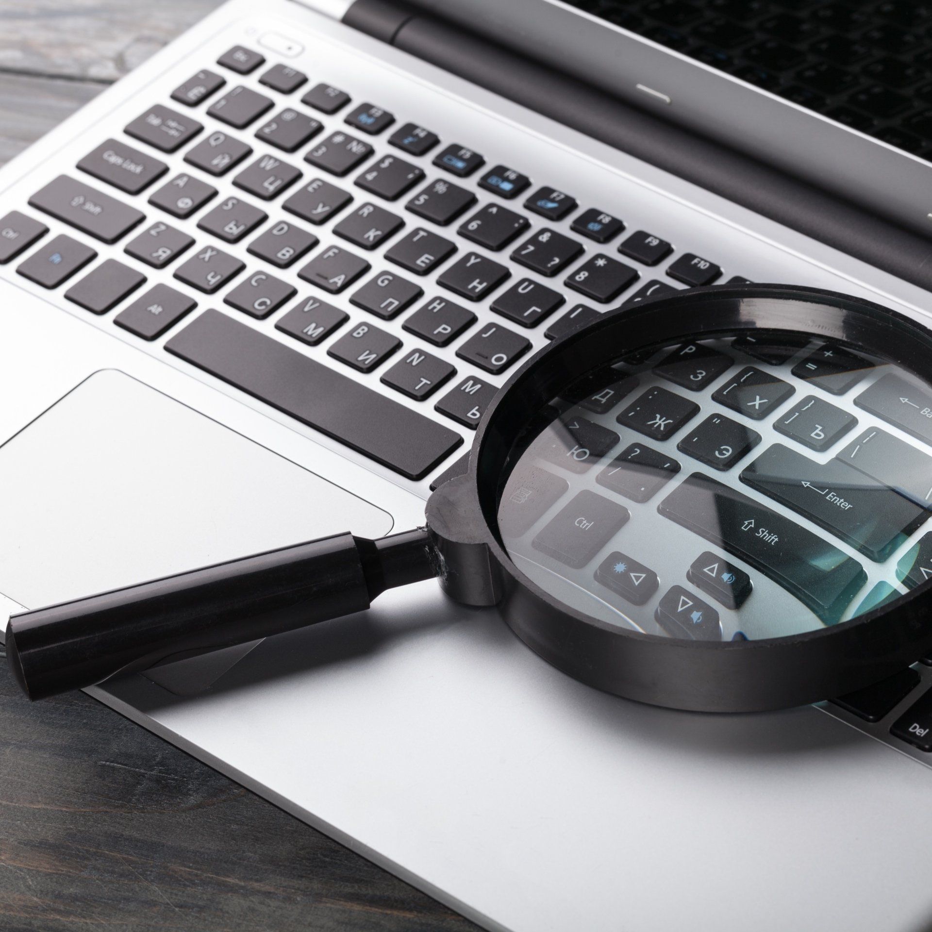 A magnifying glass is sitting on top of a laptop keyboard