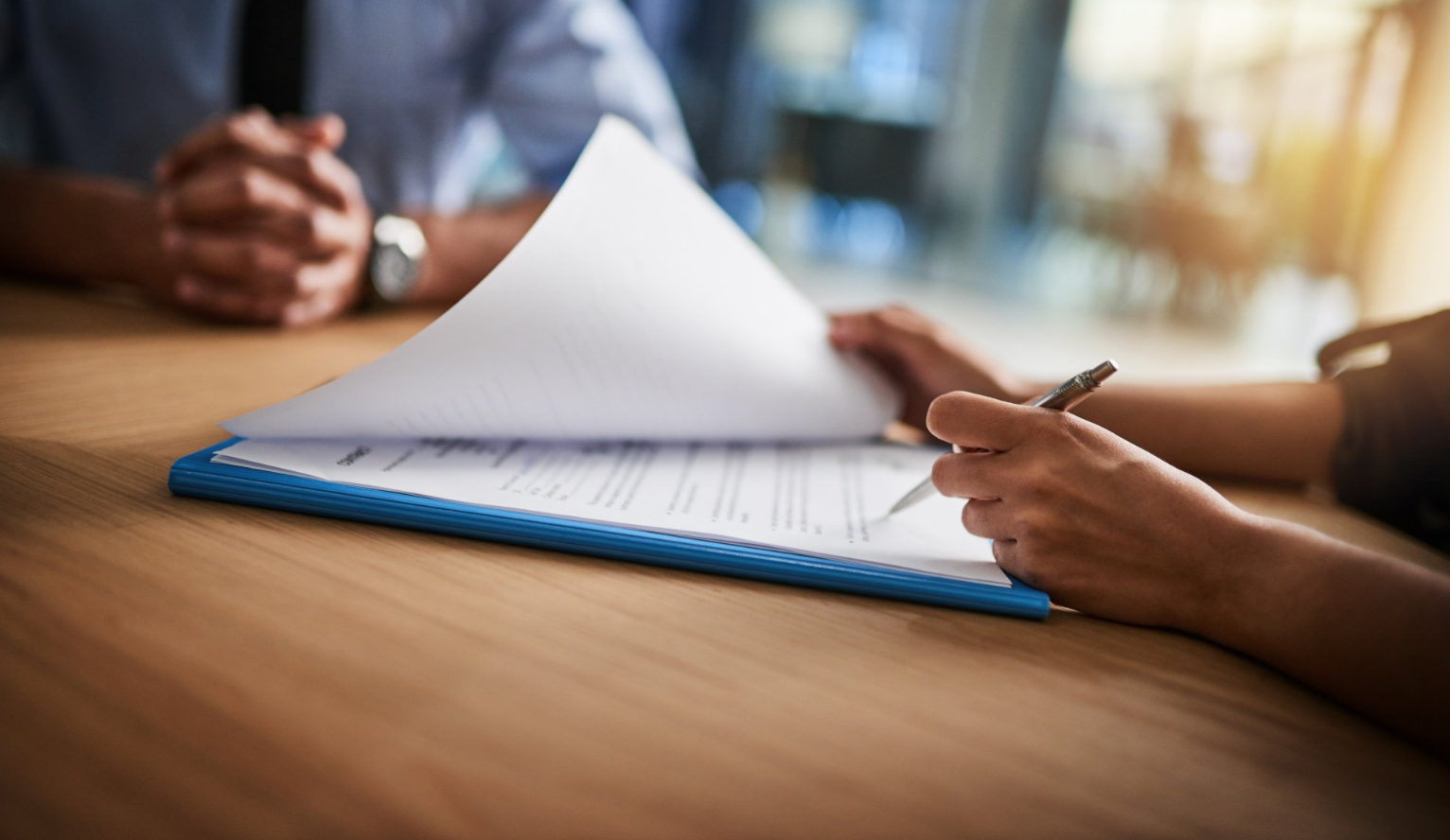 A man and a woman are sitting at a table signing a document.