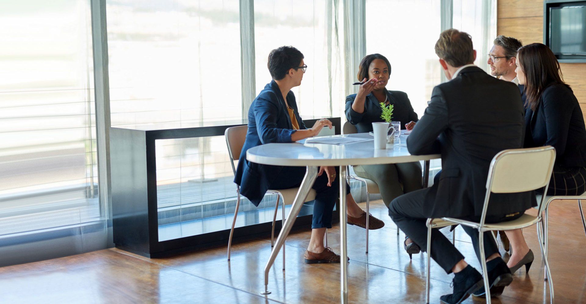 A group of people are sitting around a table having a meeting.