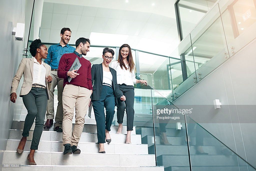 A group of business people are walking down stairs in an office building.