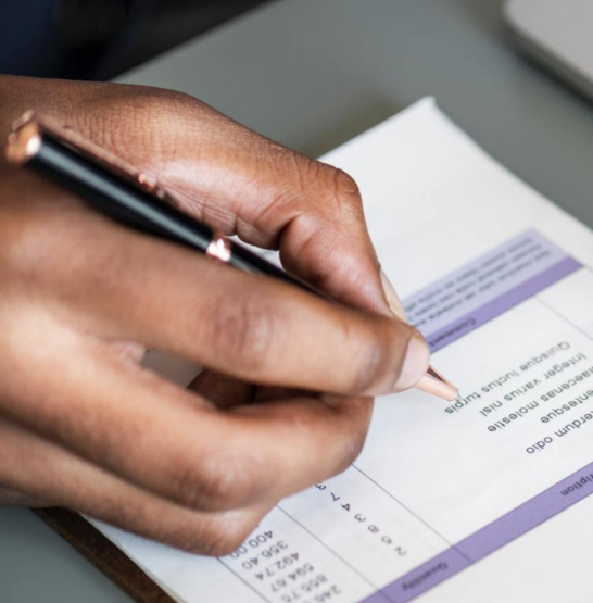 A person is writing on a piece of paper with a pen
