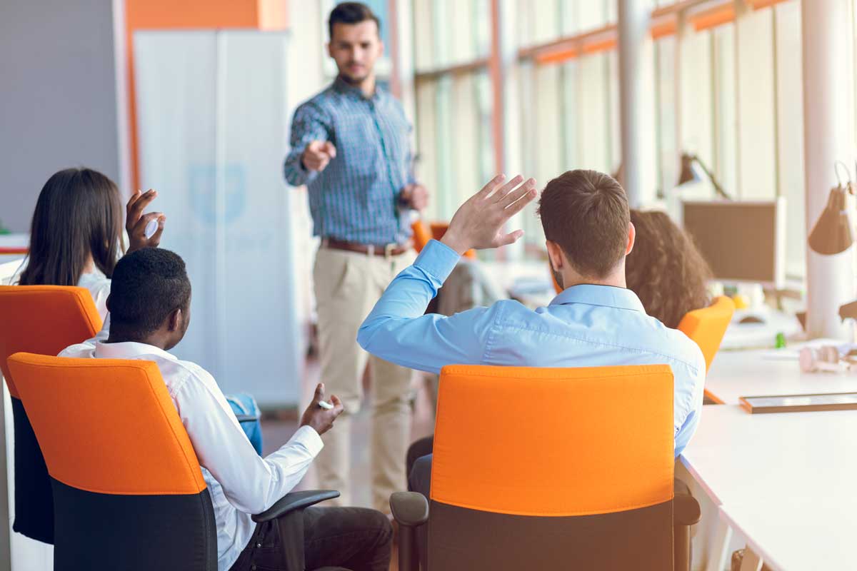 A group of people are sitting in chairs in front of a man giving a presentation.