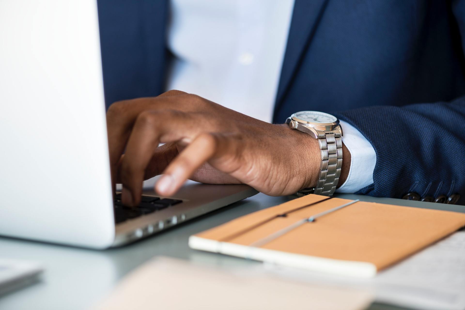 A man in a suit is typing on a laptop computer.