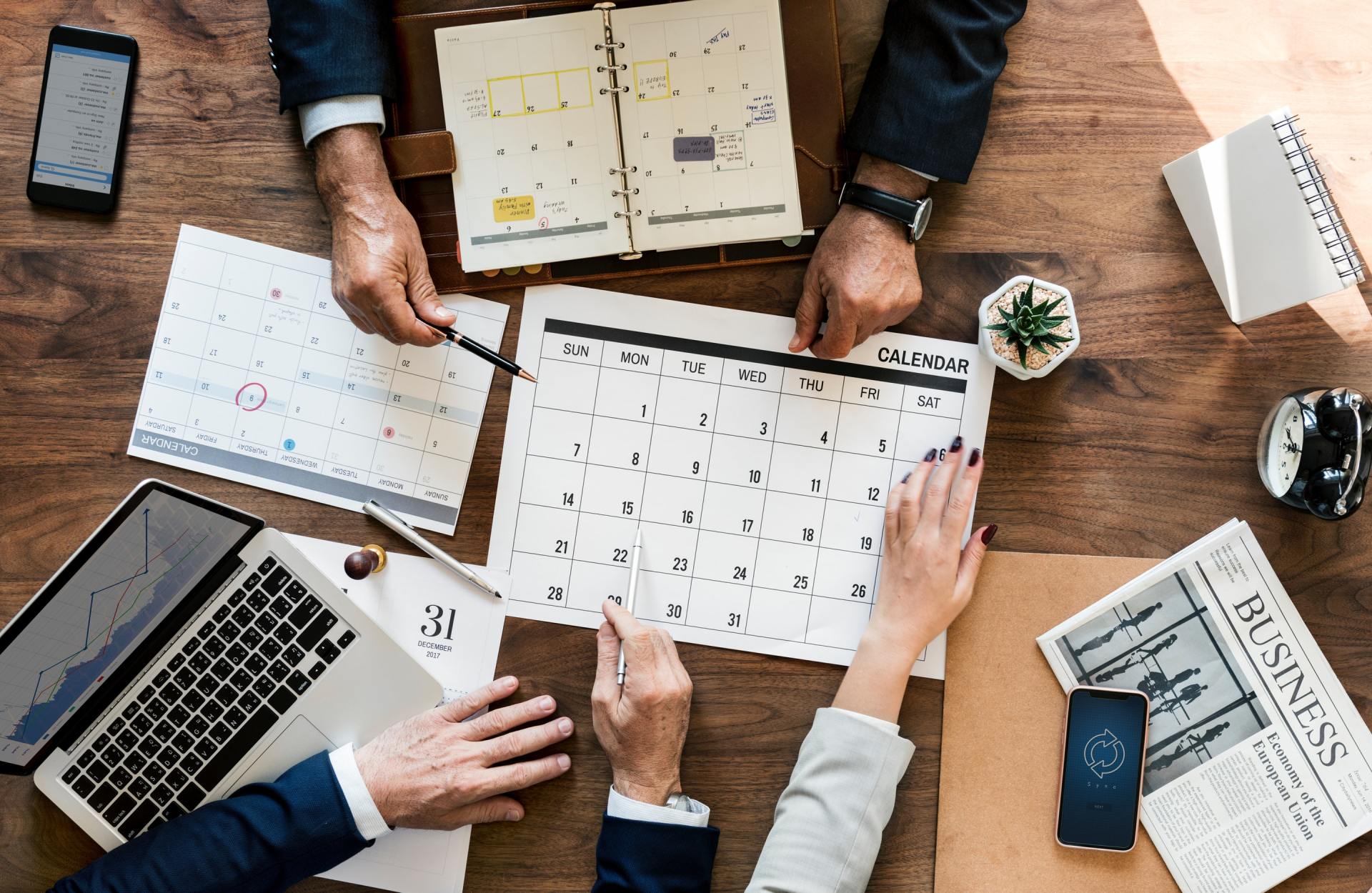 A group of people are sitting at a table looking at a calendar.